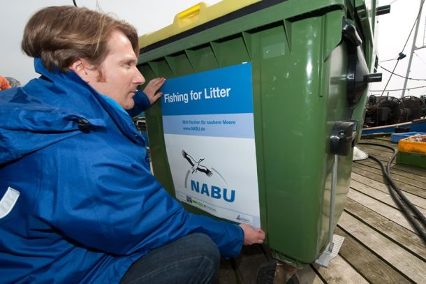 NABU-Meeresschutzexperte Kim Detloff kennzeichnet einen Sammelcontainer. Fischer können darin kostenlos Abfälle entsorgen, der sich in ihren Netzen verfangen haben.